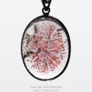 Oval pendant necklace with a glass cabochon featuring red streaks inside the pendant, hanging from a chain.